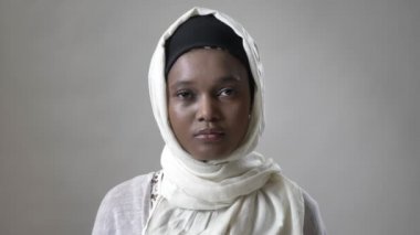 Genç Afrika Müslüman kız hijab içinde izlerken kamera, religioun kavramı, gri arka plan