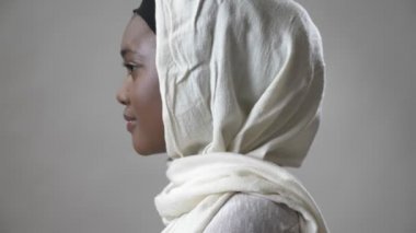 Hijab genç Afrika Müslüman kız baş dönme ve kamera, religioun kavramı, gri arka plan, izlerken