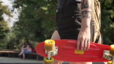 Kaykay ve bacaklar ileriye şortla tutan dövme ile el