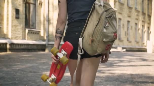 Asian young female student with tattooed hand going to university and holding skateboard and backpack, smiling and happy — Stock Video