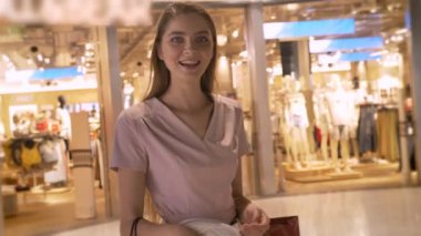 Genç çekici kız alışveriş merkezinde alışveriş gidiyor, tutan çanta, gülümseme, alışveriş kavramı, moda kavramı