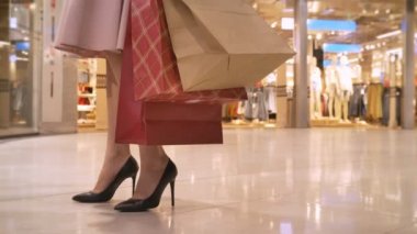 Genç kız bacaklarını alışveriş merkezinde alışveriş gider, o saatler vitrin, tutan çanta, alışveriş kavramı, moda kavramı