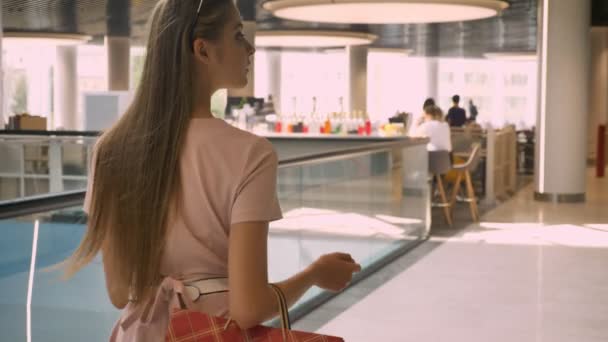 Young attractive girl goes through food court in mall, holds bags, shopping concept, fashion concept — Stock Video