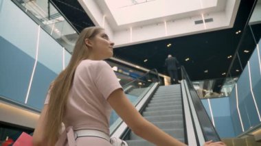 Alışveriş merkezinde yürüyen merdiven üzerinde duran genç çekici kızlar kavramı holding Çantalar kavramı, alışveriş, moda