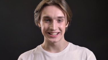 Kamera bakıyor ve gülüyor, siyah arka plan, gülümseyen mavi gözlü erkek model çekici genç adam.