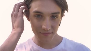 Genç yakışıklı adam kameraya bakıyor ve gülümsüyor, parlak beyaz arka plan üzerinde güzellik portre izole beyaz gömlekli