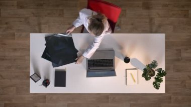 Genç kadın bilim adamı x-ray tarama arıyorsunuz ve tipik dizüstü bilgisayar, topshot, tıbbi kavramı üzerinde beyaz önlük.