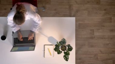 Dizüstü bilgisayarda yazarak ve masada oturan x-ray tarama, topshot, tıbbi kavramı ile beyaz montlu genç hemşire