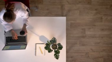 Genç kadın bilim adamı dizüstü bilgisayarda yazarak ve içme kahve, topshot, tıbbi kavramı beyaz önlük