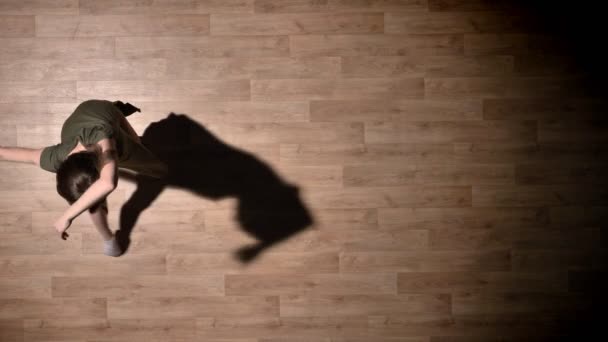 Silhouette di giovane ragazza elegante sta ballando sul pavimento in legno, concetto di balletto, concetto di movimento, colpo in alto — Video Stock
