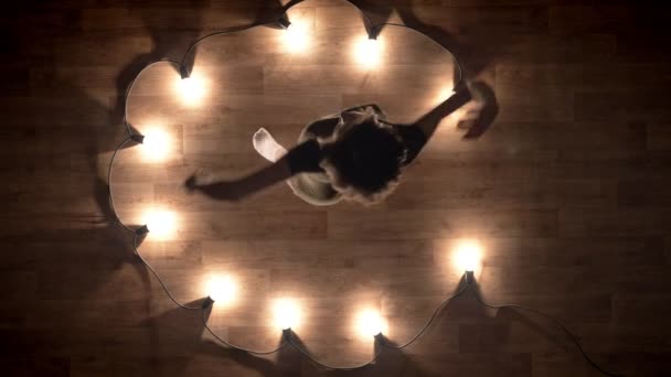 Silhouet van jong meisje ballerina is dansen op de houten vloer, flexure, lichten rond, ballet concept, verkeer concept, top shot — Stockvideo