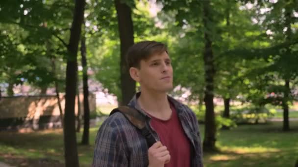 Fiatal jóképű férfi sétál a park nappali nyáron, relax koncepció — Stock videók