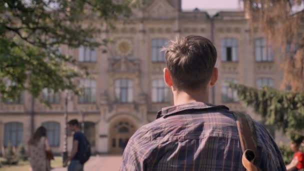 Jonge knappe man loopt door het park naar de Universiteit overdag in de zomer — Stockvideo