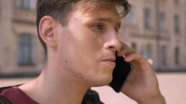 Yakışıklı delikanlı telefon parkta gündüz yaz, kamera, iletişim kavramı, arka plan bulanık, izlerken konuşuyor