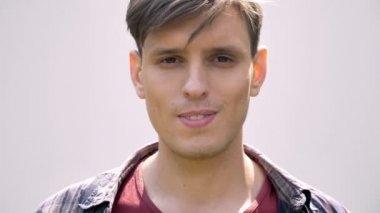 Genç yakışıklı adam gülümseyerek, kameraya, gri arka plan izlerken