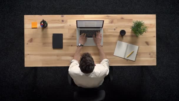 Giovane uomo sta lavorando sul computer portatile di giorno, concetto di lavoro, concetto di ufficio, concetto di comunicazione, top shot — Video Stock