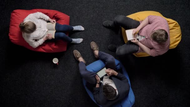 Three workers are sitting on poufs and relaxing, office concept, communication concept — Stock Video