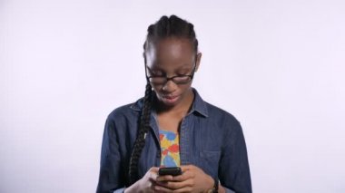 Telefon, beyaz arka plan üzerinde izole yazarak gözlüklü genç Afro-Amerikan kadın ciddi ve yoğun