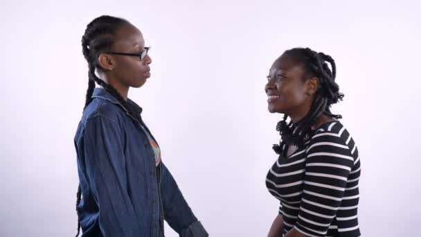 Δύο νεαρές γυναίκες αφρικανικής αμερικανικής αγκάλιασμα και βλέπουν τα φωτογραφικών μηχανών, μαύρους φίλους που απομονώνονται σε λευκό φόντο, ευτυχής και χαρούμενος — Αρχείο Βίντεο