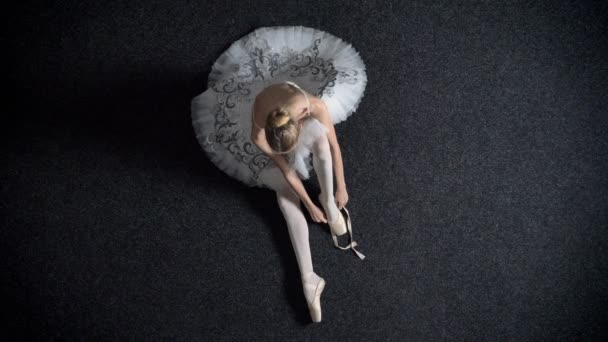 Silueta dívka balerína klade na pointe, sedící na podlaze, balet koncepce, nahoru shot — Stock video
