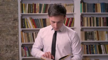 Genç işadamı kitap Kitaplığı'nda bilgi arama, kameraya izlerken, rahatla kavramı