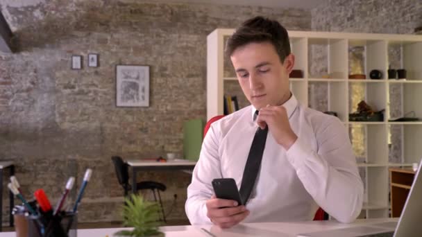 Joven hombre de negocios está trabajando con el teléfono inteligente en la oficina, mostrando la pantalla verde, punto en él, concepto de negocio, concepto de comunicación — Vídeos de Stock