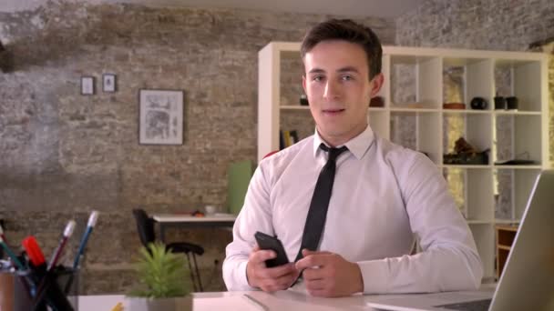 Молодий привабливий бізнесмен працює зі смартфоном в офісі, показуючи зелений екран, вказуючи на нього, бізнес-концепцію, концепцію комунікації — стокове відео