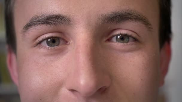 Lächelnde Augen junger attraktiver Geschäftsmann schaut in die Kamera — Stockvideo
