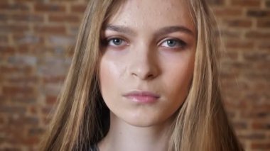 Kamera, tuğla arka plan, arka plan bulanık, izlerken genç ciddi bayan yüzü.