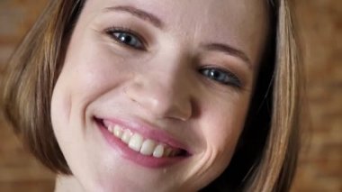 Yüz genç mutlu kız gülümseyerek, kameraya, tuğla arka plan izlerken