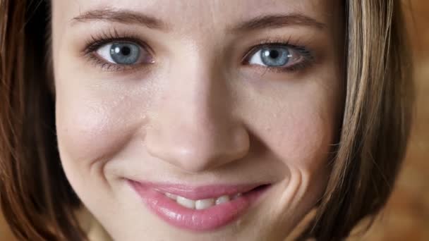 Rostro de joven chica tímida atractiva está sonriendo, mirando a la cámara, fondo de ladrillo — Vídeos de Stock