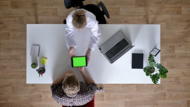 Mladá žena doktora ukazuje zelené obrazovky na tabletu pacient, muž u lékaře, zdravotnické koncepce, nahoru shot — Stock video