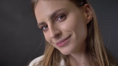 Genç tatlı kız yüzünü izlerken kamera, flört kavramı, gri arka plan