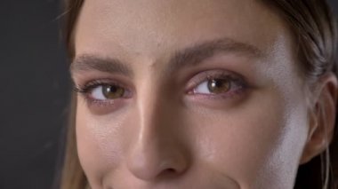 Tabii ki genç utangaç kız kameraya gülümseyen, gri arka plan, izlerken