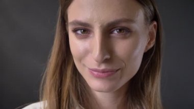 Kendine güvenen genç kız yüzünü kameraya gülümseyen, gri arka plan, izliyor