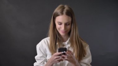 Genç güzel kız smartphone, gülümseyen, iletişim kavramı, gri arka plan ileti bağlıyor