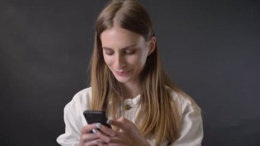 Genç güzel kız smartphone, tıkınma saç, iletişim kavramı, gri arka plan ileti bağlıyor