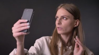 Genç kız sheaks görüntülü smartphone, iletişim kavramı, gri arka plan üzerinde içinde serin