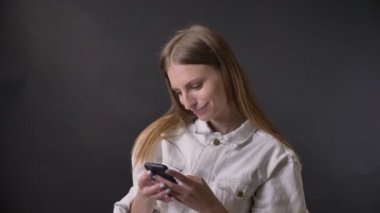Genç güzel kız Smartphone cep telefonu ile fotoğraf izliyor, o taşınır, iletişim kavramı, gri arka plan