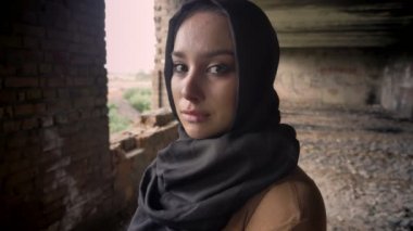 Hijab ağlıyor içinde genç üzücü Müslüman kadın portresi silahlı asker, terk edilmiş binada arka plan, askeri kavram yürümeye
