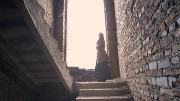 Jeune femme musulmane réfugiée dans le hijab debout seule dans un bâtiment abandonné et regardant autour de elle, inquiète et terrifiée — Video