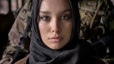 Yakın kamera, silahlı asker kadın, askeri kavram arkasında silah duran ile bakarak hijab genç Müslüman kadın portresi