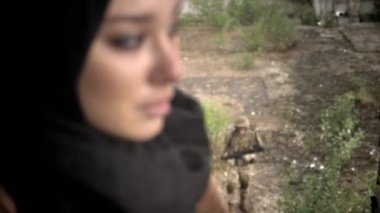 Torna ve kameraya, seyir hijab üzgün Müslüman kadında genç silahlı adam silah dışında yürüme, yağmurlu bir gün, terörizm kavramı ile