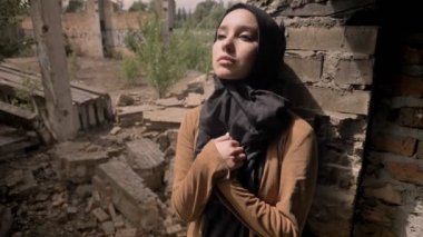 Hijab harap tuğla bina ve kameraya, üzgün ve depresyonda seyir yakın duran genç Müslüman kadın