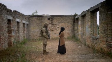 Silahlı asker ve hijab harap tuğla bina ve birbirimizi, savaş kavramı içinde duran genç Müslüman kadın