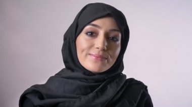 Genç Müslüman kız hijab içinde gözlerini açar ve gülümseyen, dini kavramı, gri arka plan fotoğraf makinesi, saatler