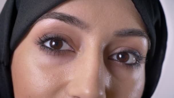 Olhos de menina muçulmana grave jovem no hijab está assistindo a câmera, fundo cinza — Vídeo de Stock