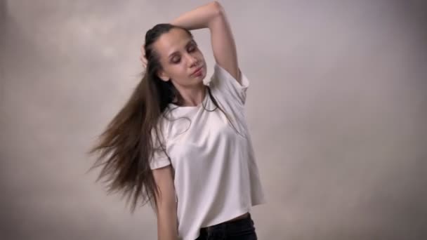 Jonge brunette meisje dansen en springen, glimlachen, verkeer concept, grijze achtergrond — Stockvideo