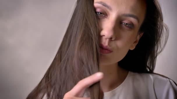 Giovane ragazza bruna sexy sta ballando, rimboccare i capelli, flirtare concetto, sfondo grigio — Video Stock