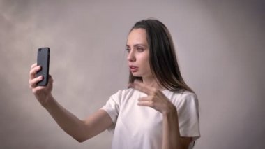 Genç esmer kız video aramasý smartphone, iletişim kavramı, gri arka plan vardır